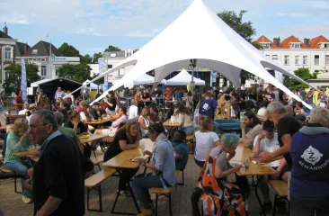 Prins Hendrikplein tijdens Zeeheldenfestival met tent, eettafels en gezellige sfeer.
